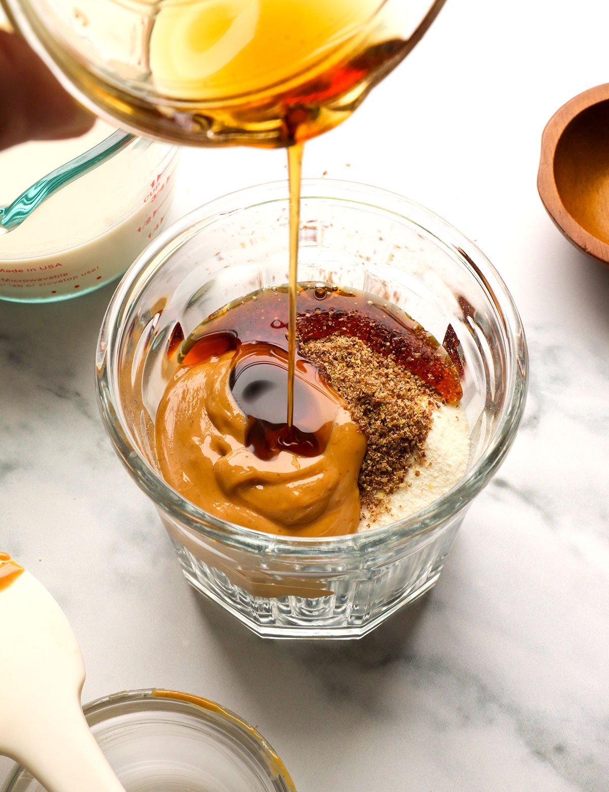 maple syrup added to a jar of oats with peanut butter and ground flax. 