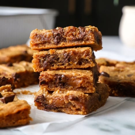 peanut butter blondies stacked on parchment paper to show their texture.