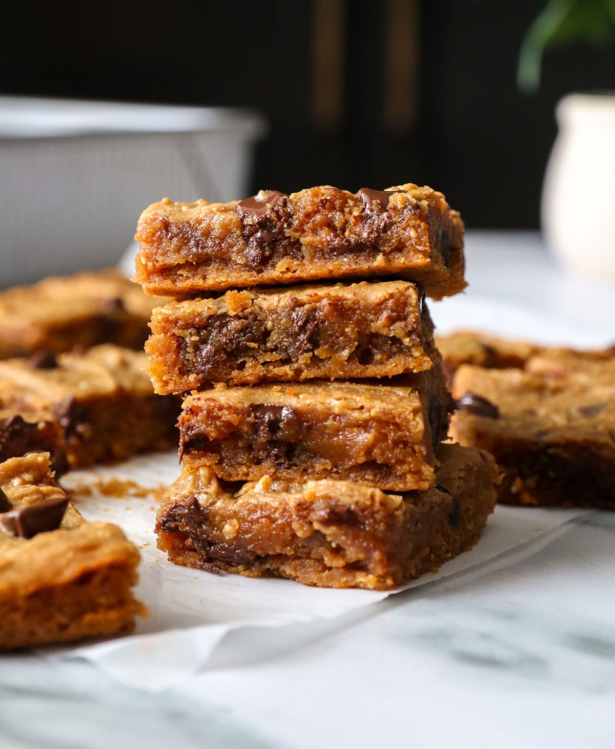 peanut butter blondies stacked on parchment paper to show their texture.