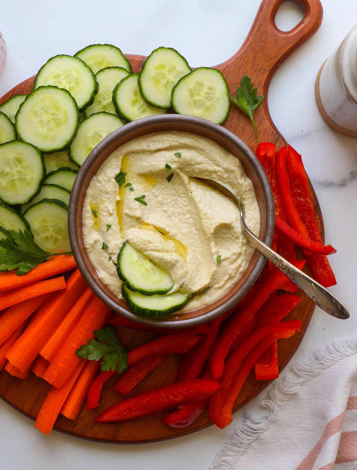 zucchini hummus served with sliced cucumbers and other veggies.