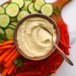 keto hummus served in a bowl with sliced veggies on a board.