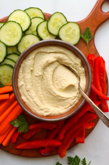 keto hummus served in a bowl with sliced veggies on a board.