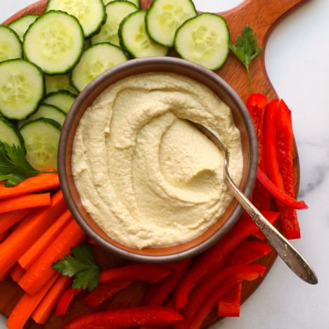 keto hummus served in a bowl with sliced veggies on a board.