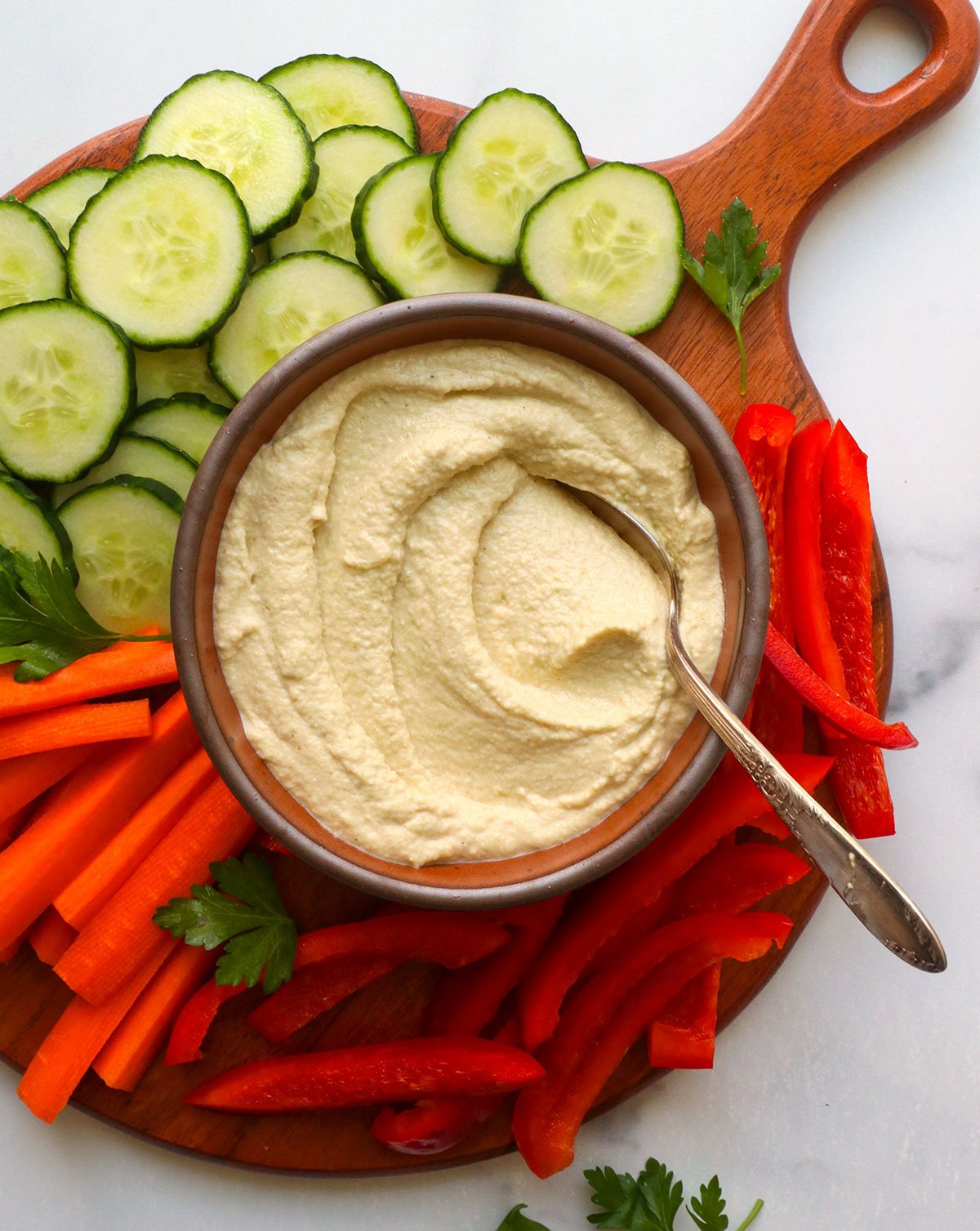 keto hummus served in a bowl with sliced veggies on a board. 