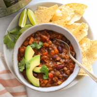 instant pot vegan chili served in a bowl with tortilla chips and sliced avocado.