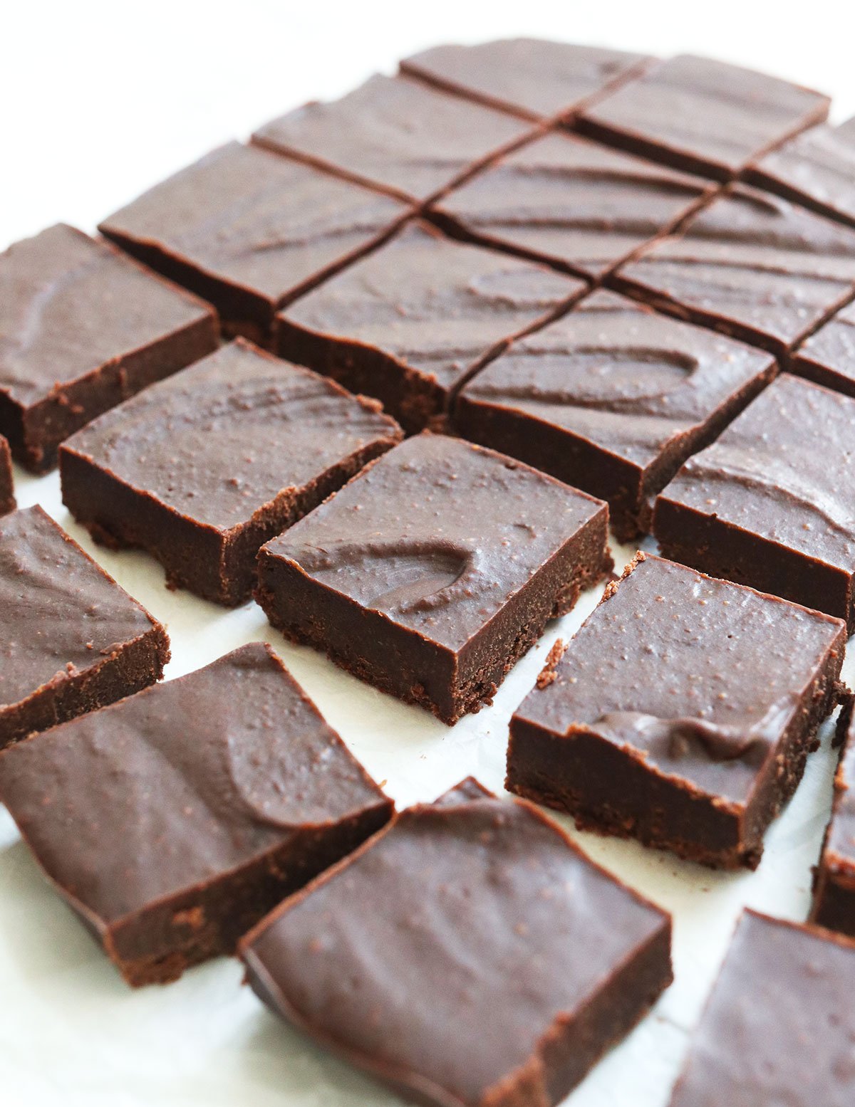 freezer fudge sliced into squares on parchment paper.