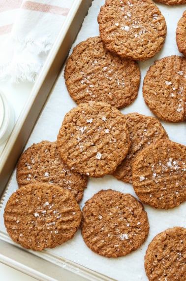 almond butter cookies scattered on a pan with sea salt.