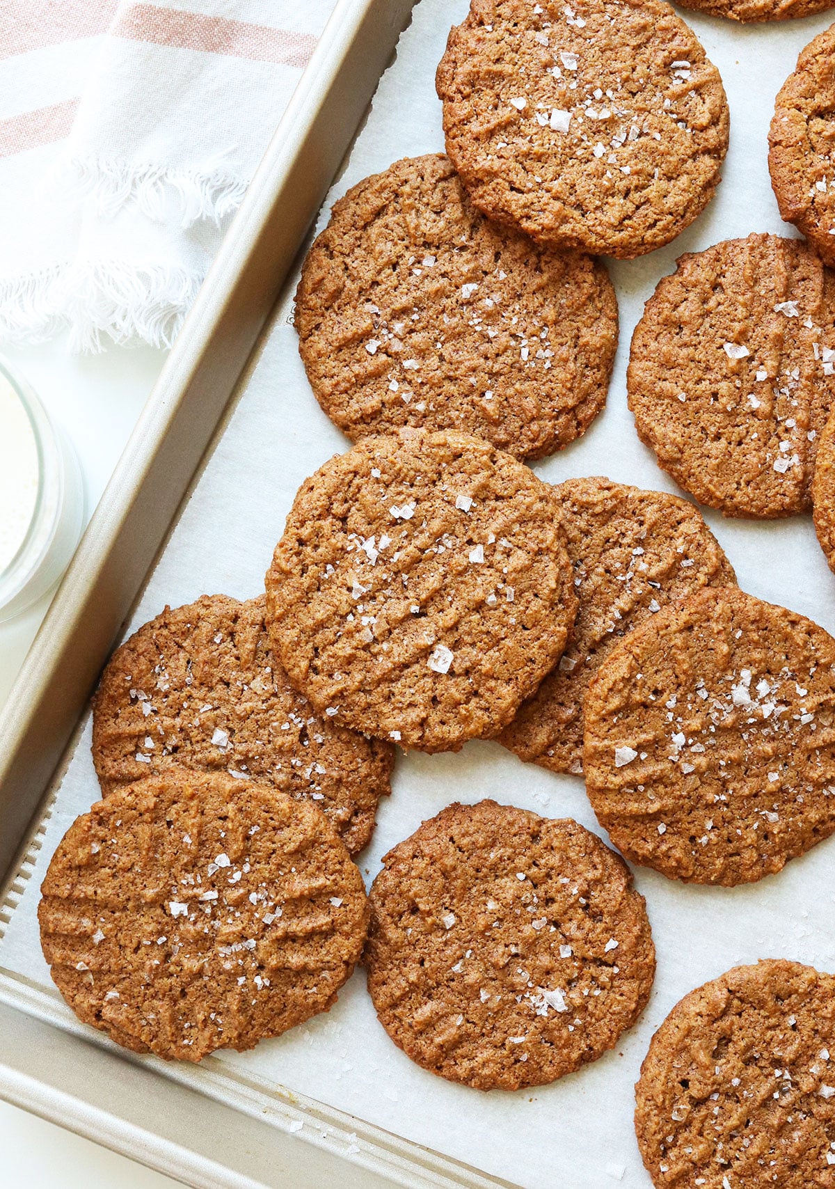 almond butter cookies scattered on a pan with sea salt.