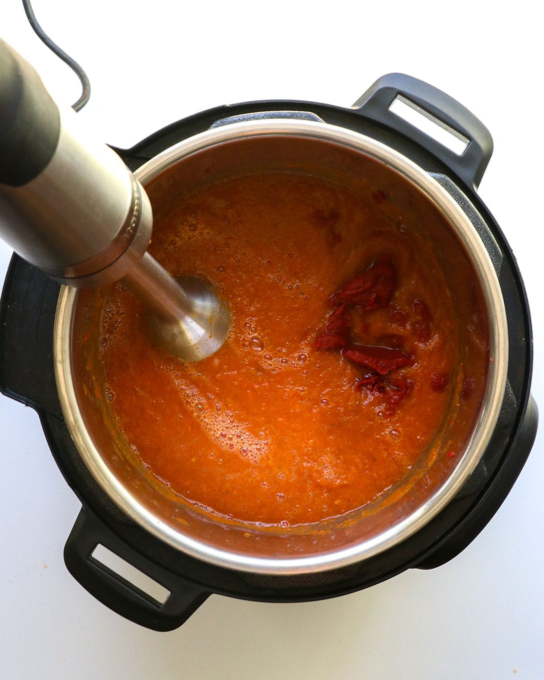 Tomato paste added to sauce with an immersion blender. 