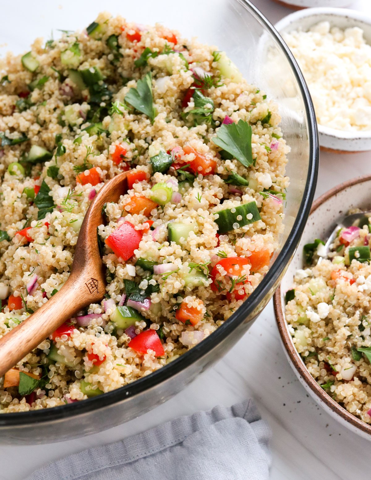 Quinoa salad in large glass serving bowl with spoon.