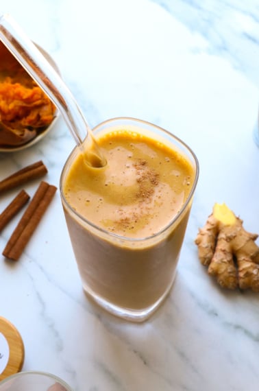 sweet potato smoothie near ginger and cinnamon sticks in a glass.