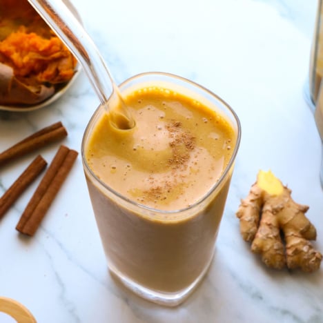 sweet potato smoothie near ginger and cinnamon sticks in a glass.