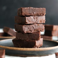 vegan freezer fudge stacked on a dark plate.