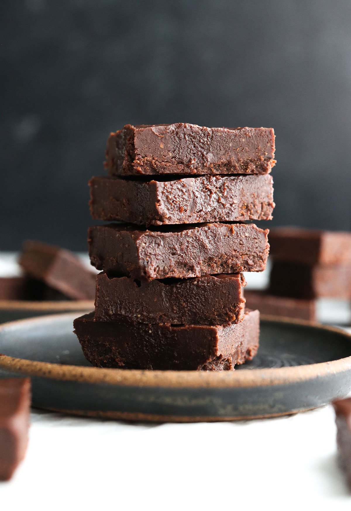 vegan freezer fudge stacked on a dark plate.