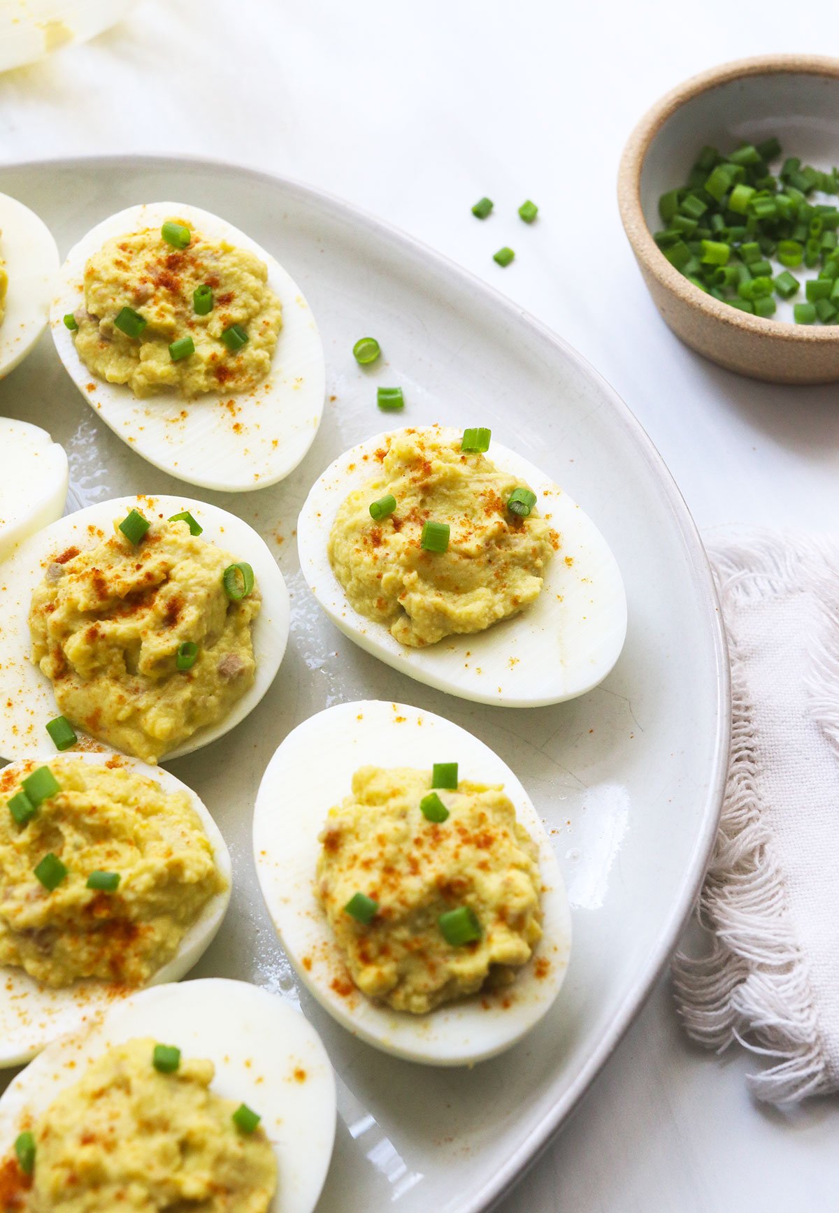 avocado deviled eggs topped with paprika and chives.