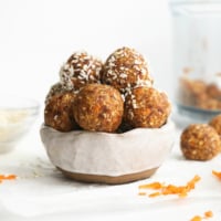 carrot cake bites stacked in a white bowl.