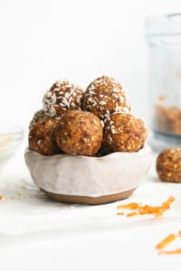 carrot cake bites stacked in a white bowl.