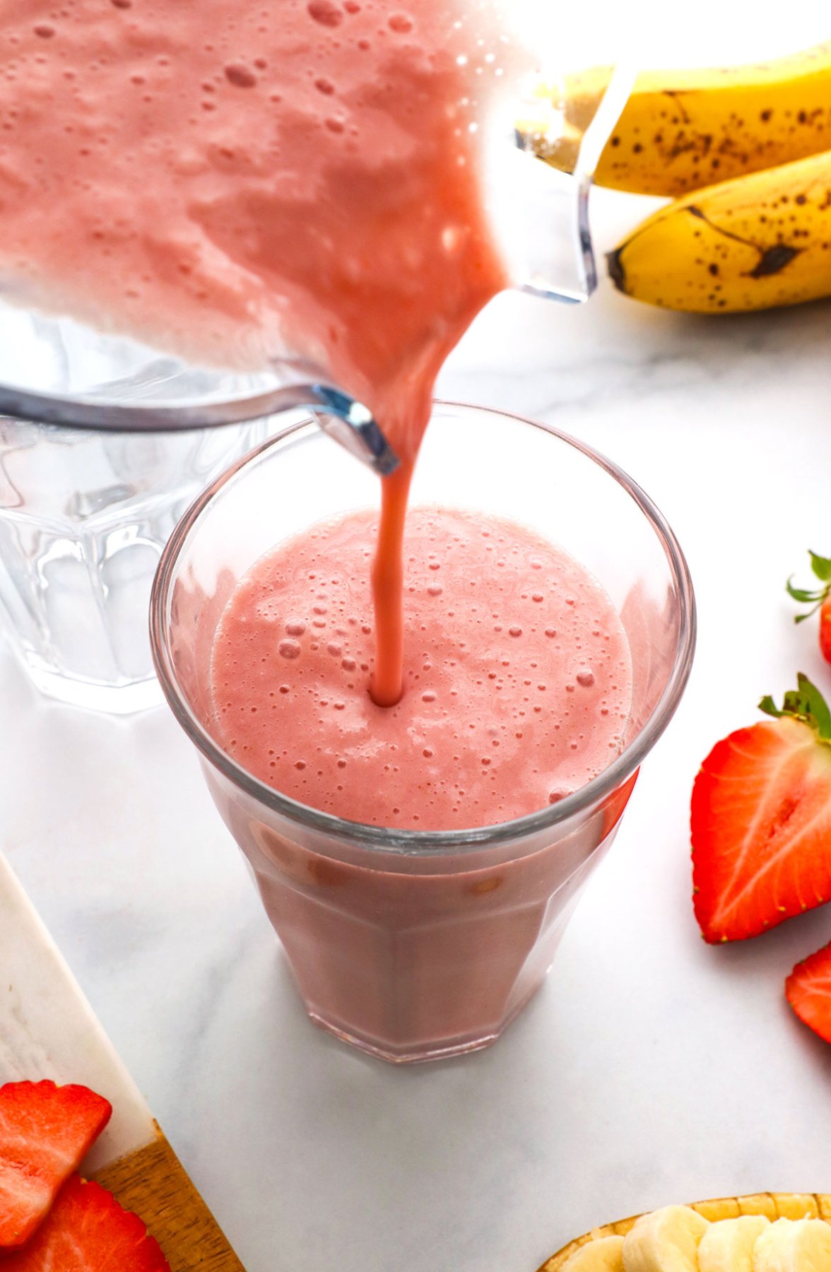 strawberry banana smoothie poured from a blender into a glass.