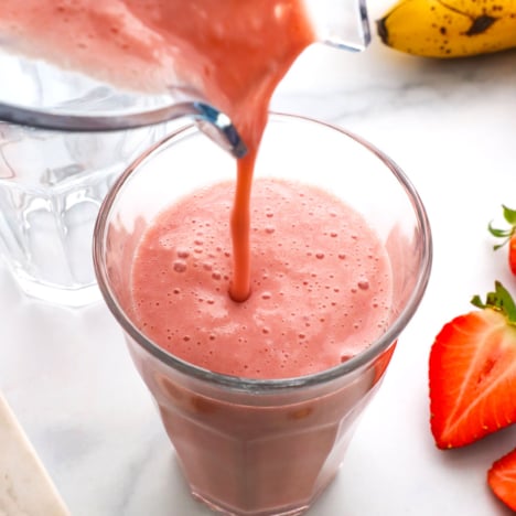 strawberry banana smoothie poured from a blender into a glass.