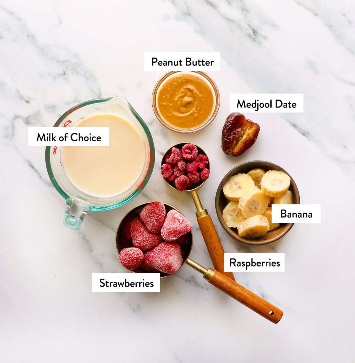 Le lait, la banane, les fraises, les framboises et le beurre de cacahuète sont écrits dans des tasses. 
