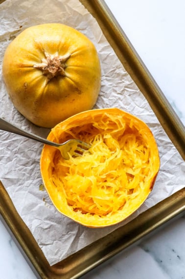 spaghetti squash prepared on a baking sheet and fluffed with a fork.