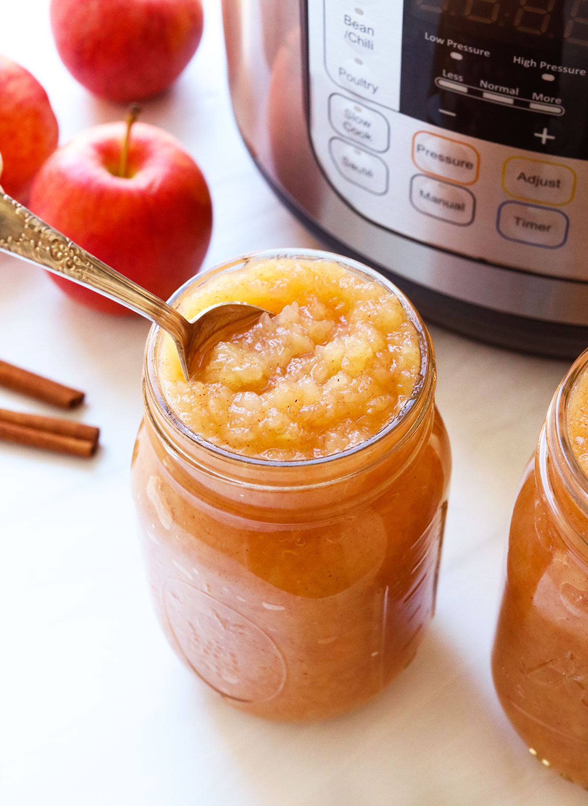 Instant Pot applesauce in two mason jars with a spoon.