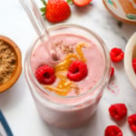 peanut butter jelly smoothie in a glass with raspberries on top.
