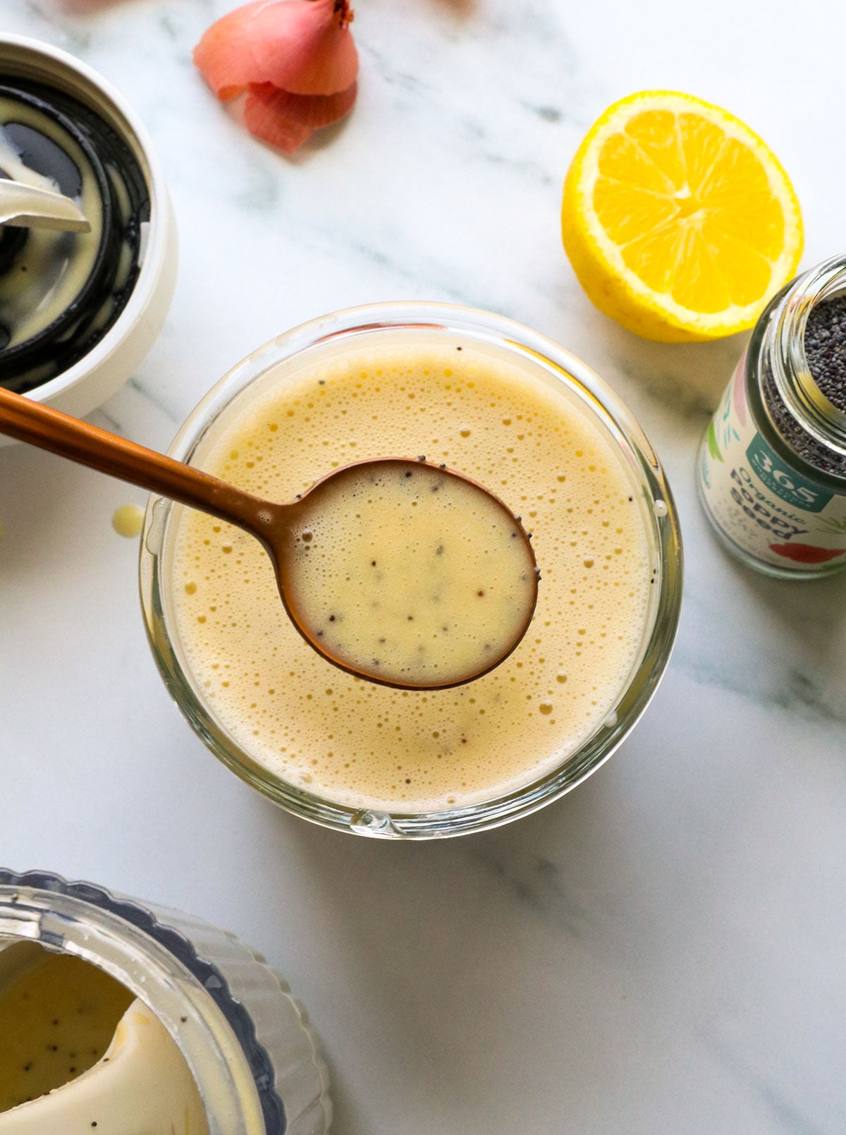 poppy seed dressing lifted on a spoon from a glass jar.