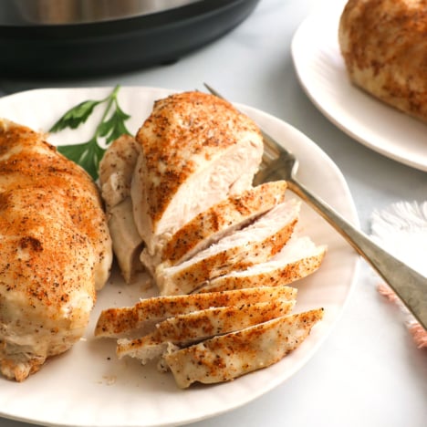 sliced chicken on a plate in front of the Instant Pot.