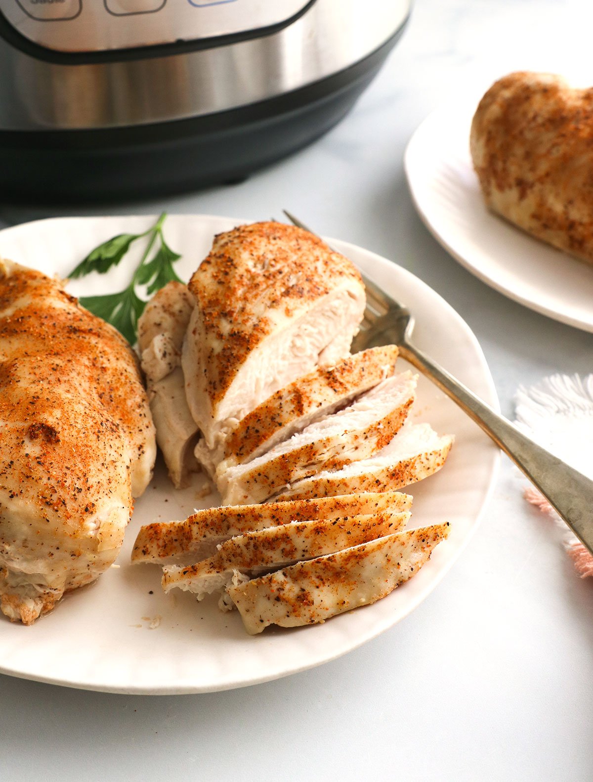 sliced chicken on a plate in front of the Instant Pot.