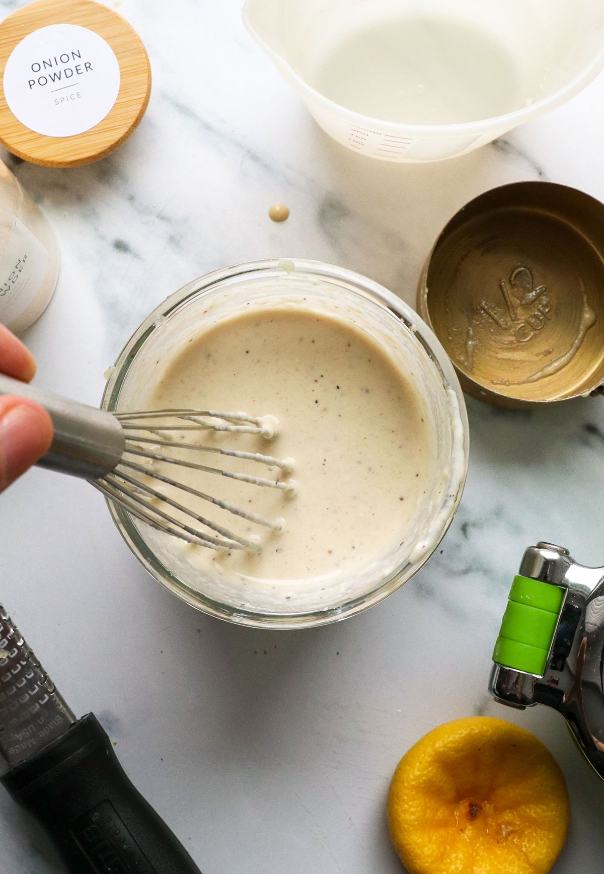 tahini dressing mixed with a small whisk in a glass jar. 