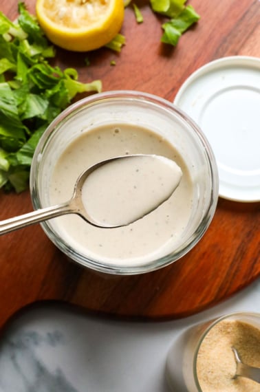 tahini dressing on a spoon over a jar of dressing.
