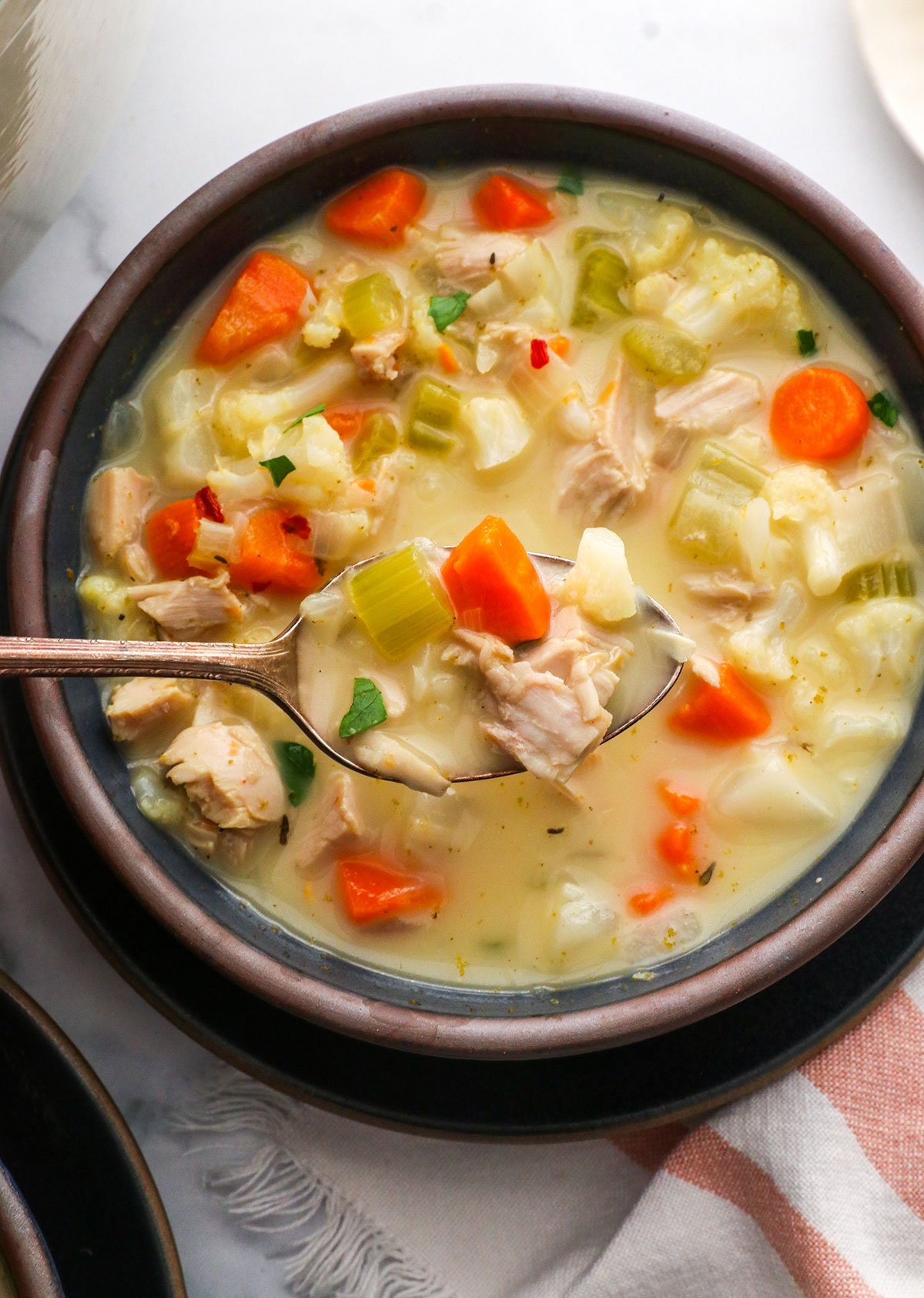 leftover turkey soup lifted on a spoon over a bowl.