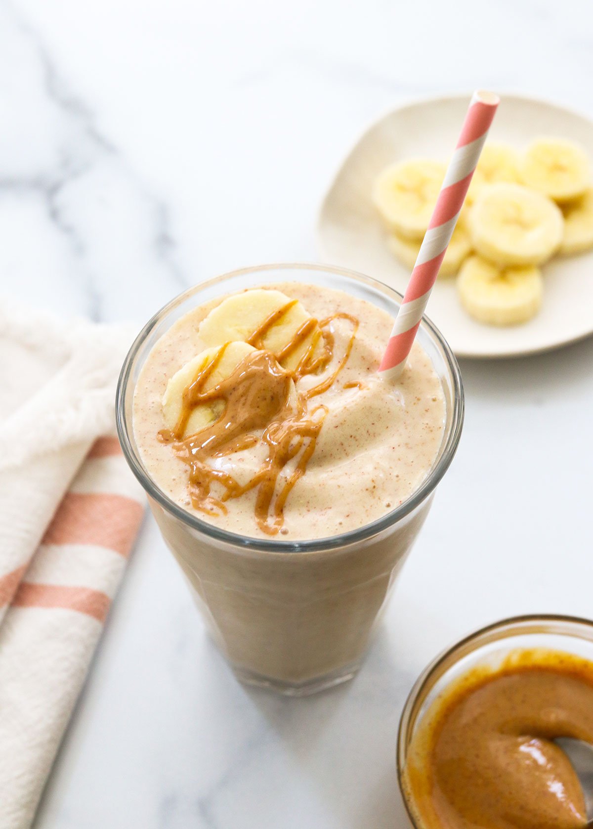 Peanut butter banana smoothie served with a pink striped straw. 