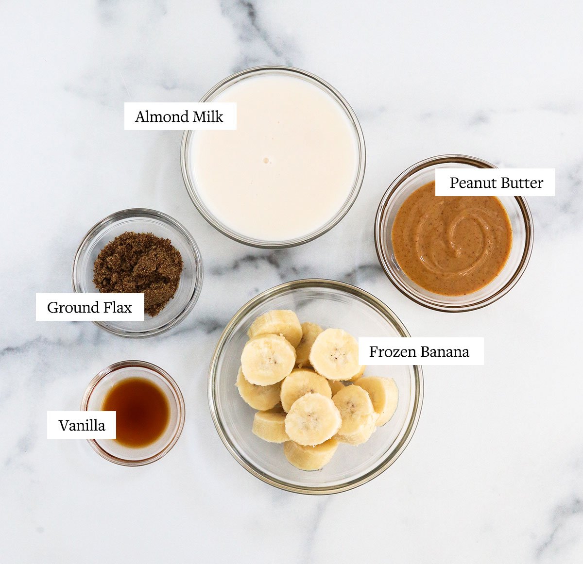 peanut butter banana smoothie ingredients labeled in glass bowls. 