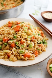 cauiflower fried rice served on plate with chopsticks.
