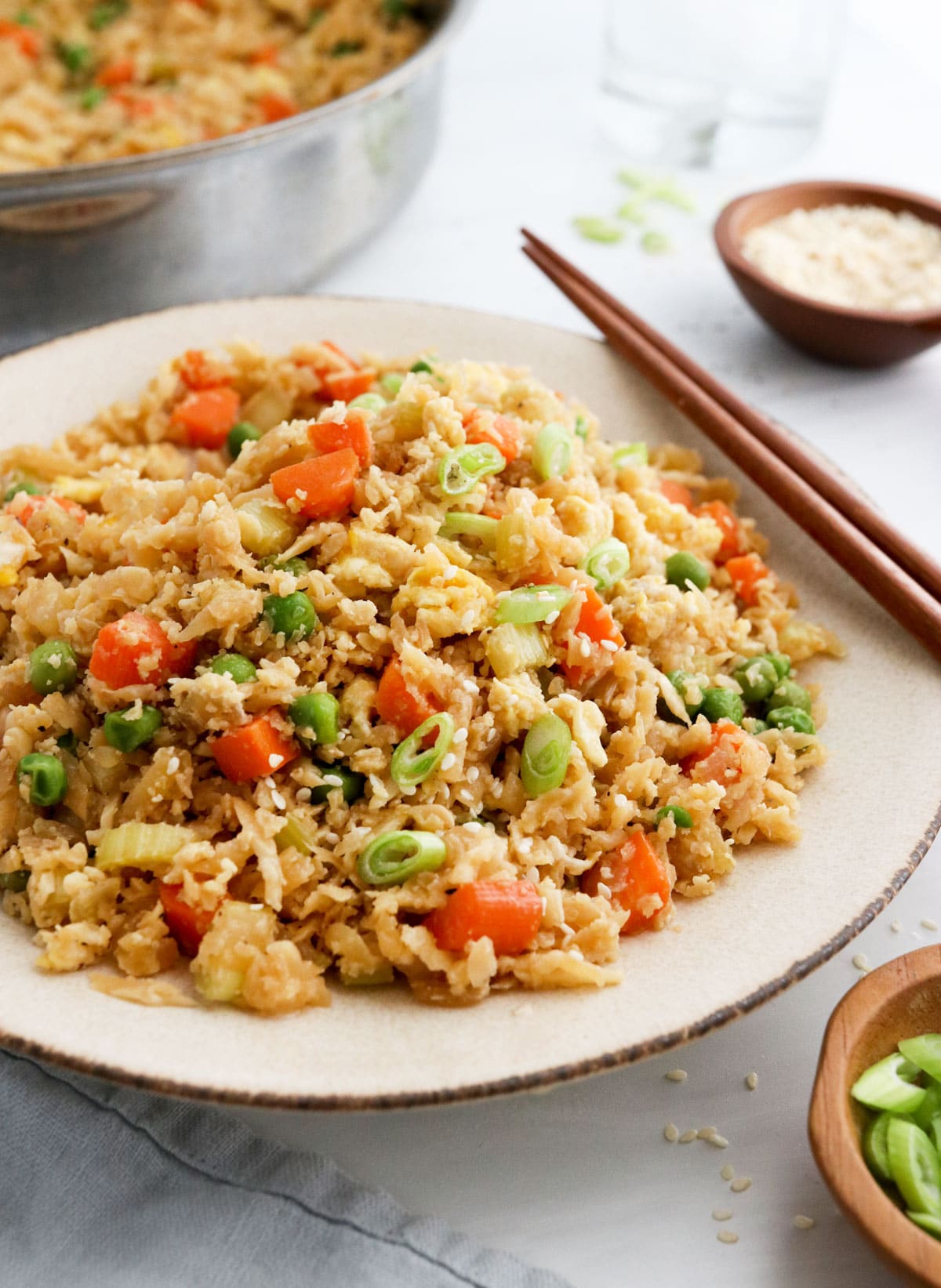 cauiflower fried rice served on plate with chopsticks.