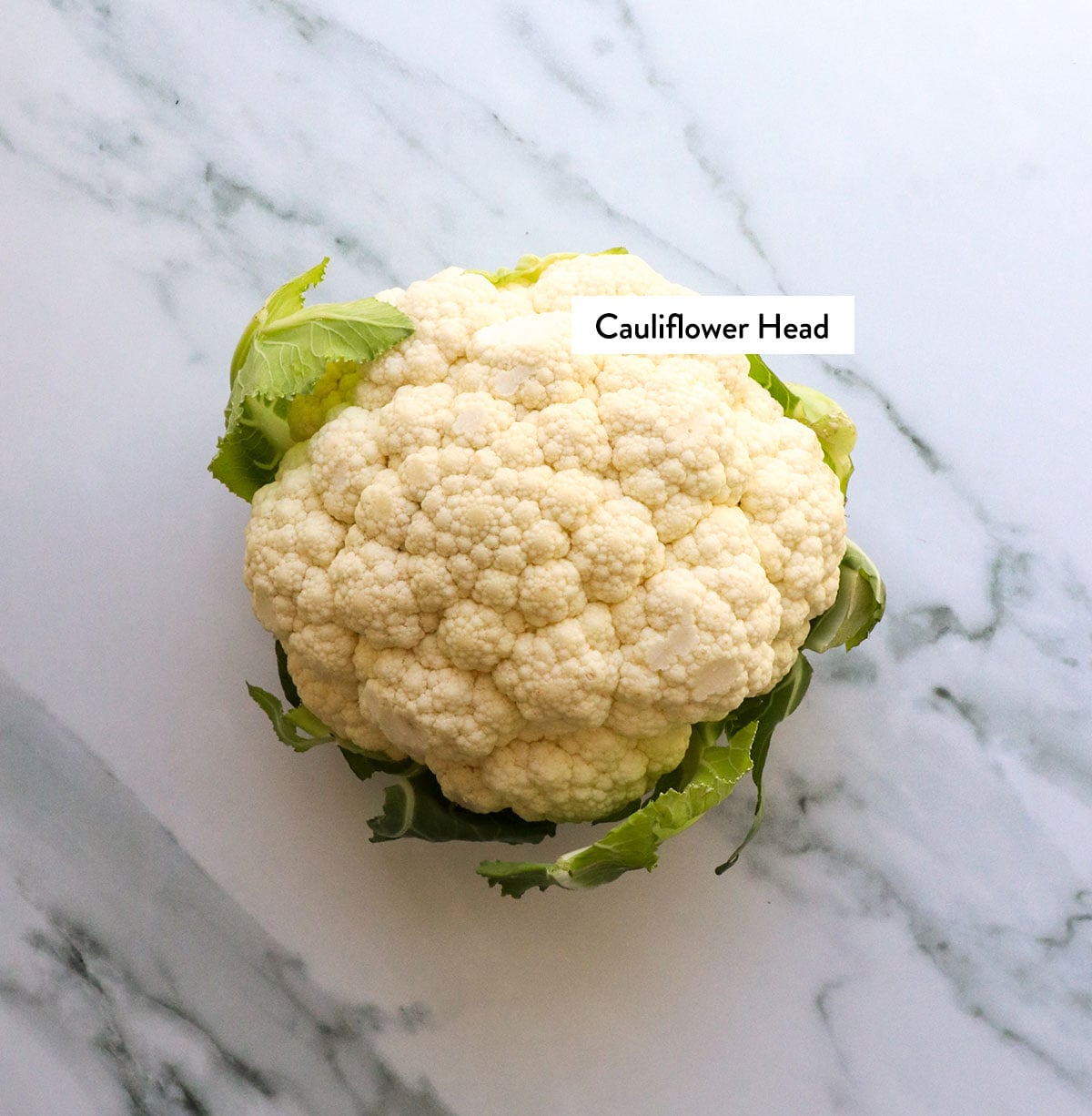 head of cauliflower labeled on a marble surface.