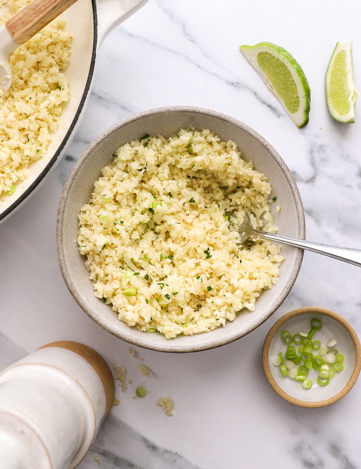 cooked cauliflower rice in a bowl with green onion.
