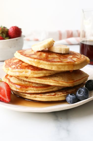 stack of coconut flour pancakes topped with bananas and syrup.
