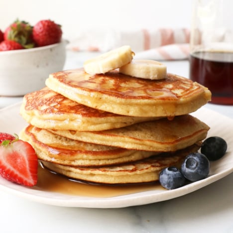stack of coconut flour pancakes topped with bananas and syrup.