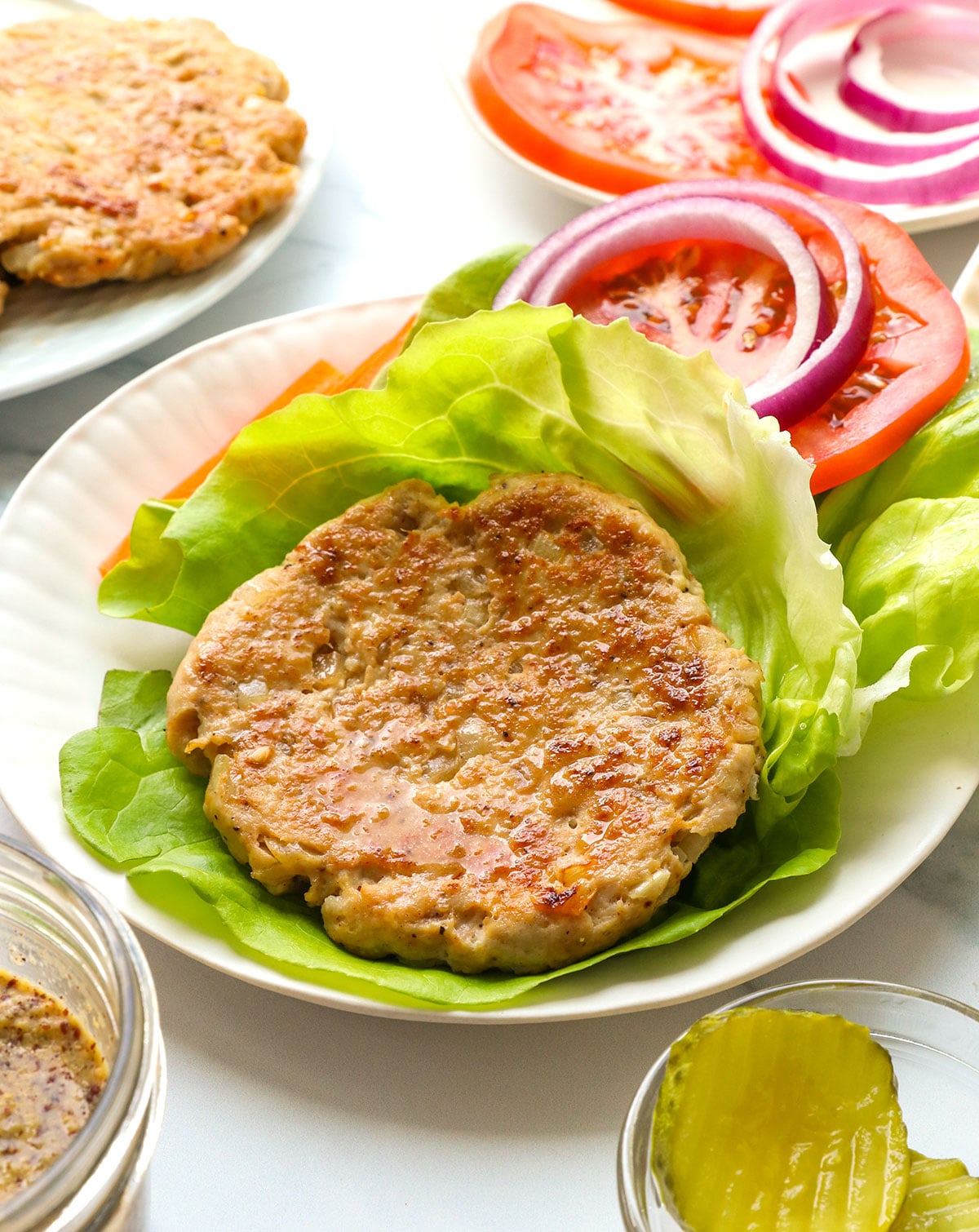 chicken burger served on a lettuce wrap with toppings.