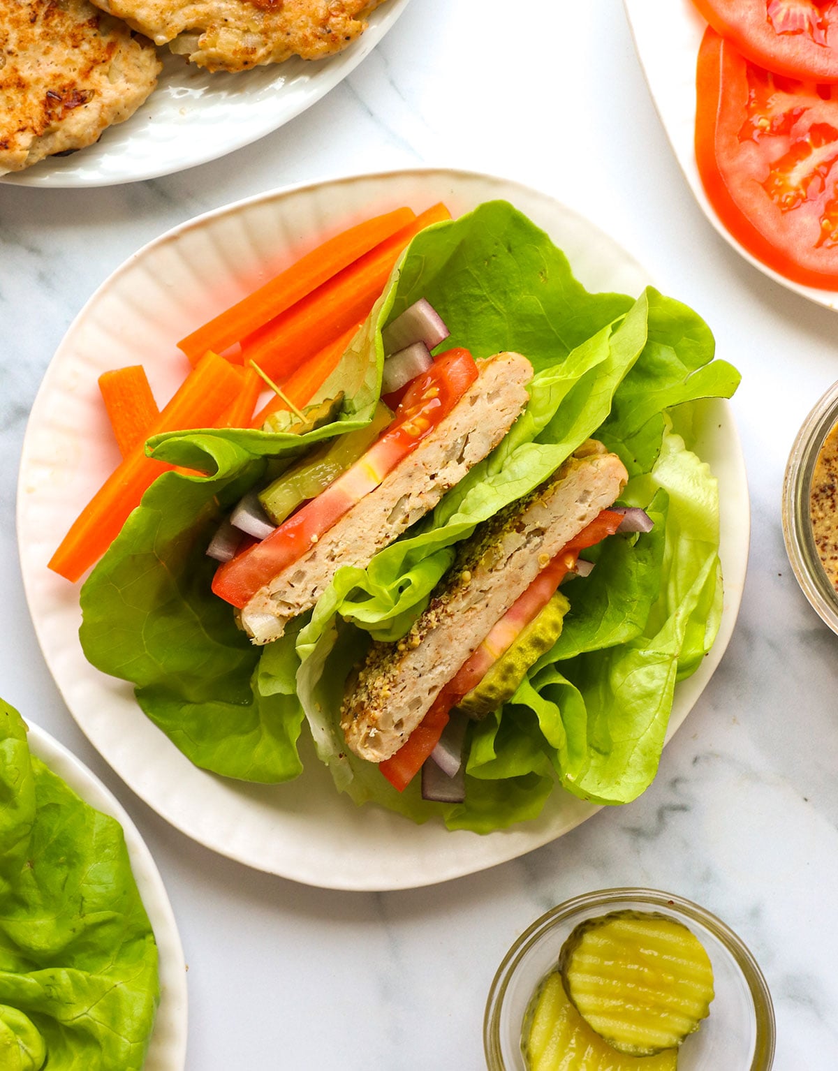 chicken burger served in a lettuce wrap with tomato, pickles and mustard.