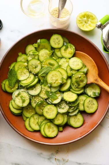 Asian cucumber salad served in a brown bowl with fresh herbs on top.