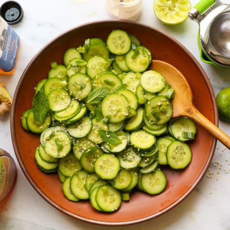 Asian cucumber salad served in a brown bowl with fresh herbs on top.