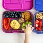 kid lunch box with hand reaching for grapes