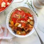 White bowl filled with quinoa and cooked ratatouille with a fork.