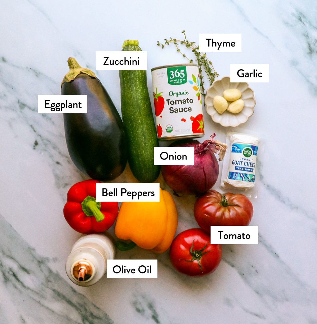 White surface topped with eggplant, zucchini, bell peppers, tomatoes, and red onion.