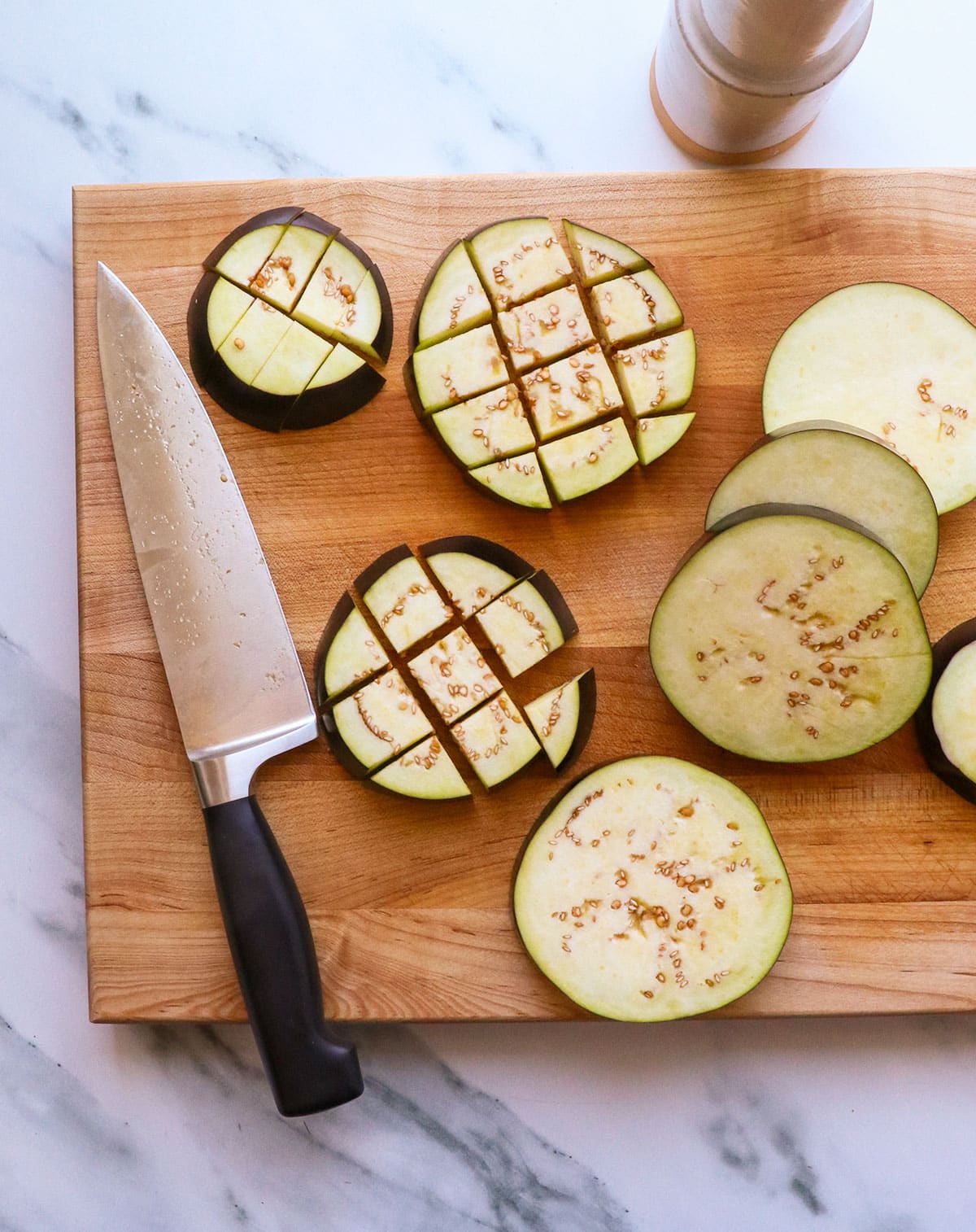 eggplant sliced and then cut into chunks on a cutting board.