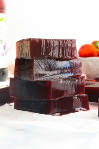 Vegan Jello made with grape juice stacked on parchment paper.